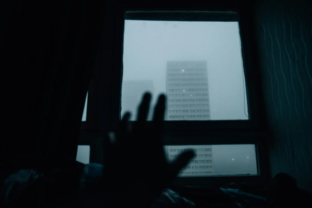 夜明け前の窓に手を伸ばす。部屋は暗く、外は青い