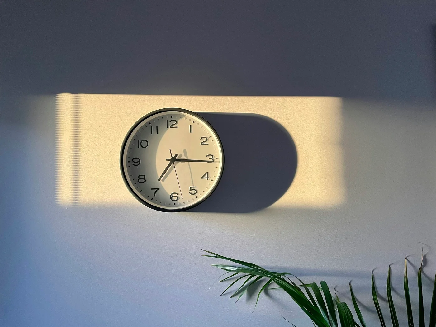 壁の時計に朝の光が当たっている