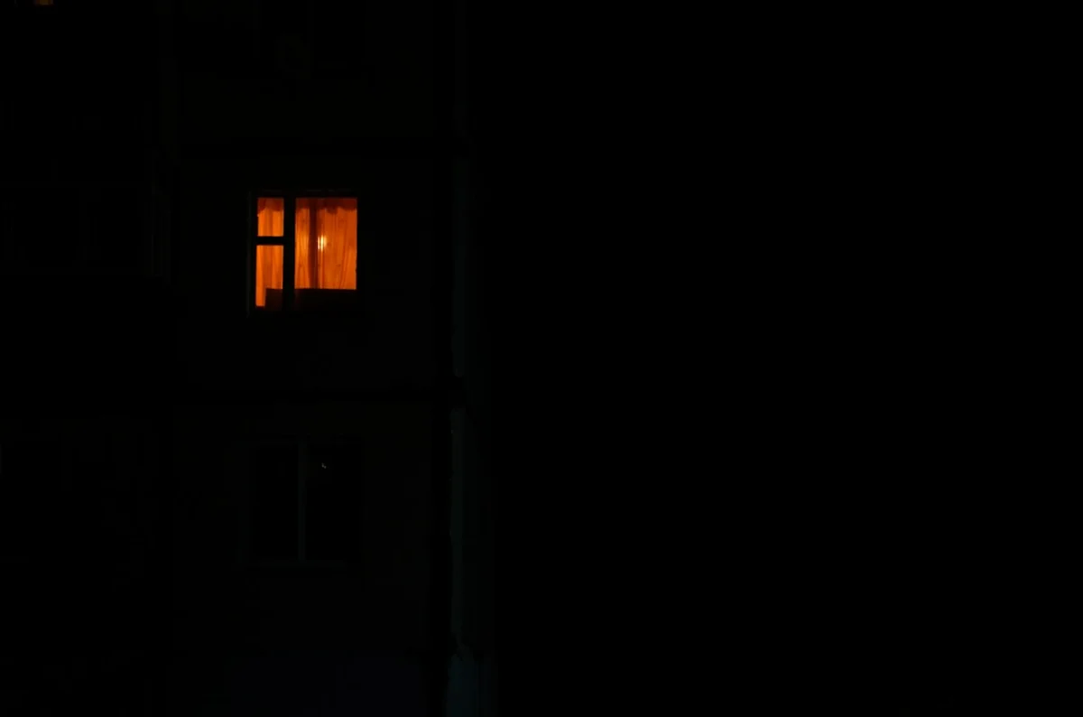 夜の暗い建物に、ひとつだけ明かりのついた窓