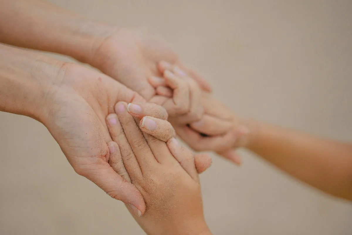 大人の両手が、子どもの小さな手をそっと包み込んでいる