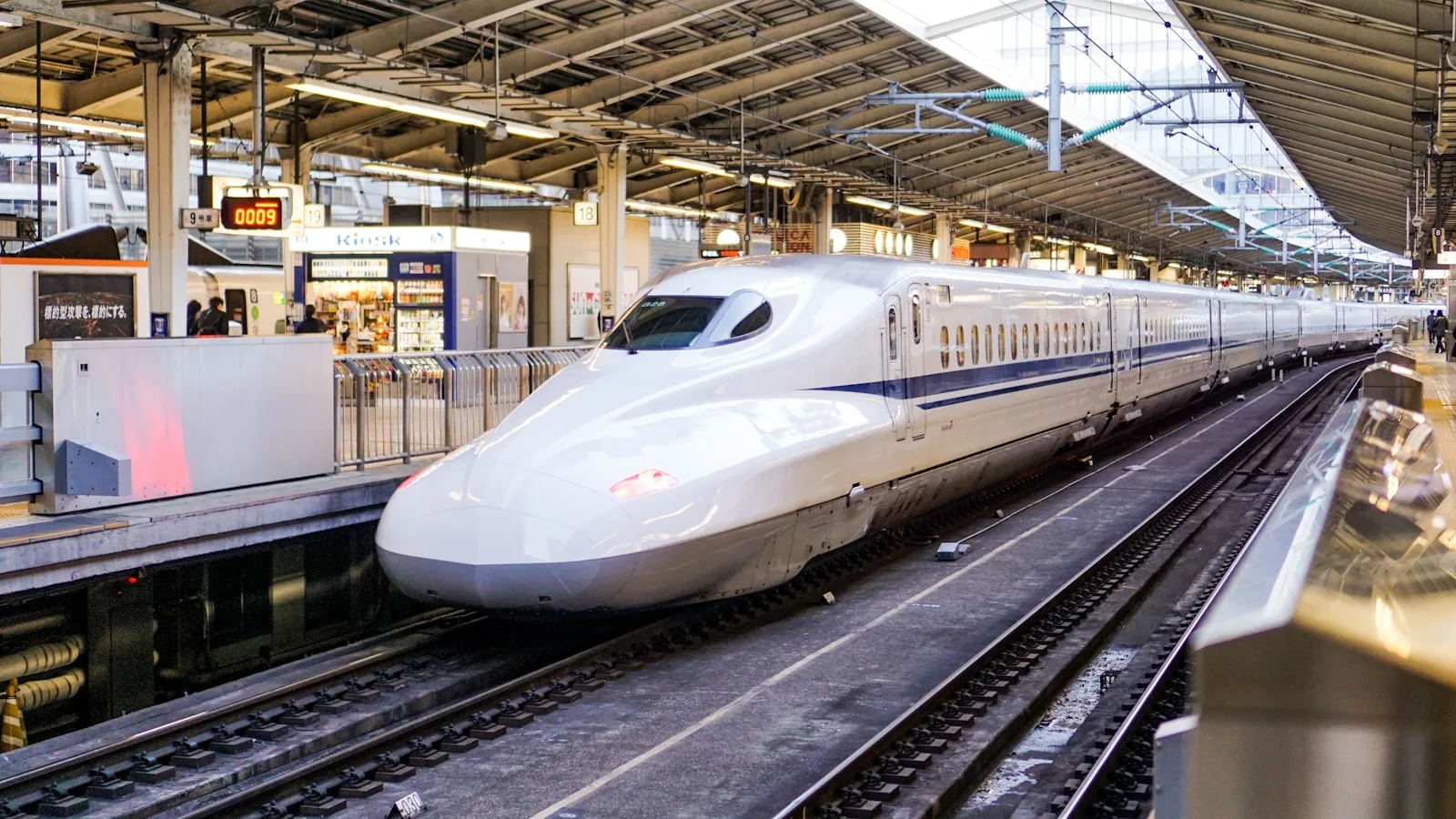新幹線のホームに停まる白い車両。旅立ちの気配が漂う駅の風景
