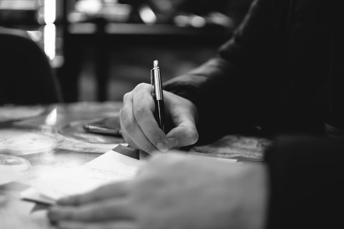 紙にペンで書き込んでいる手元