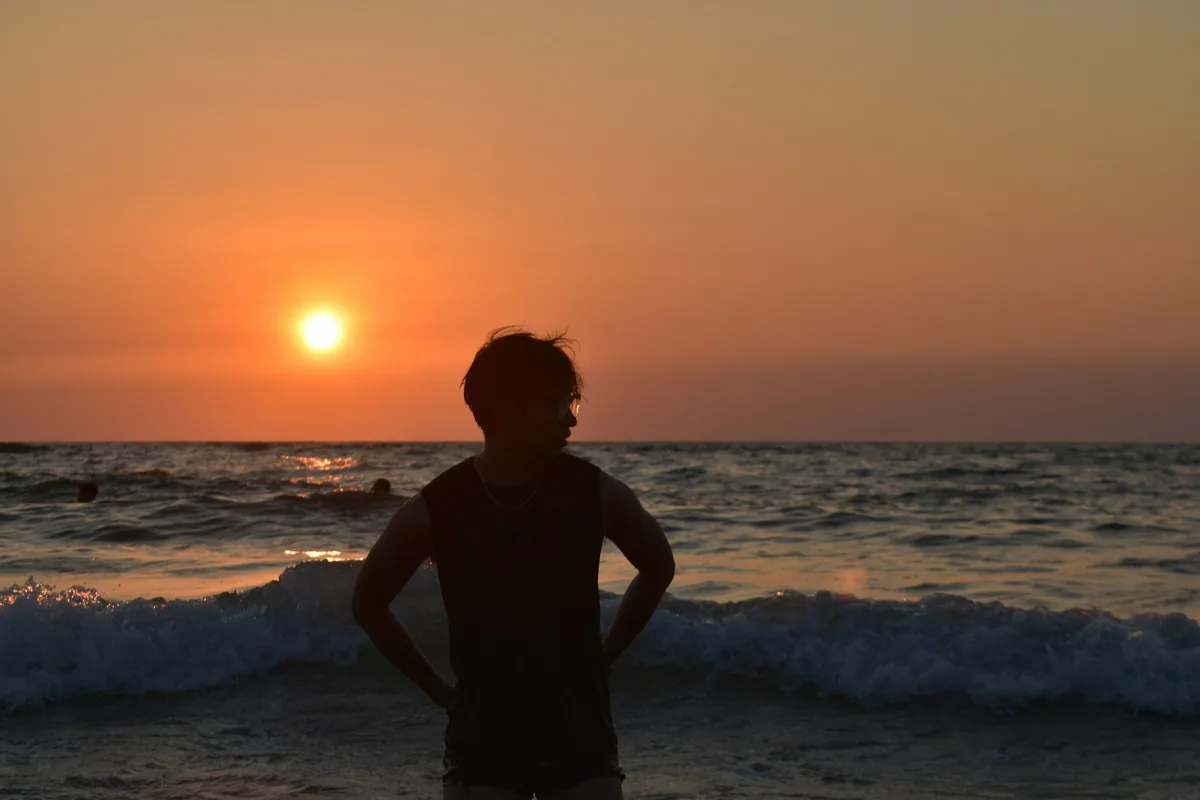 夕暮れの海辺に立つ人の後ろ姿