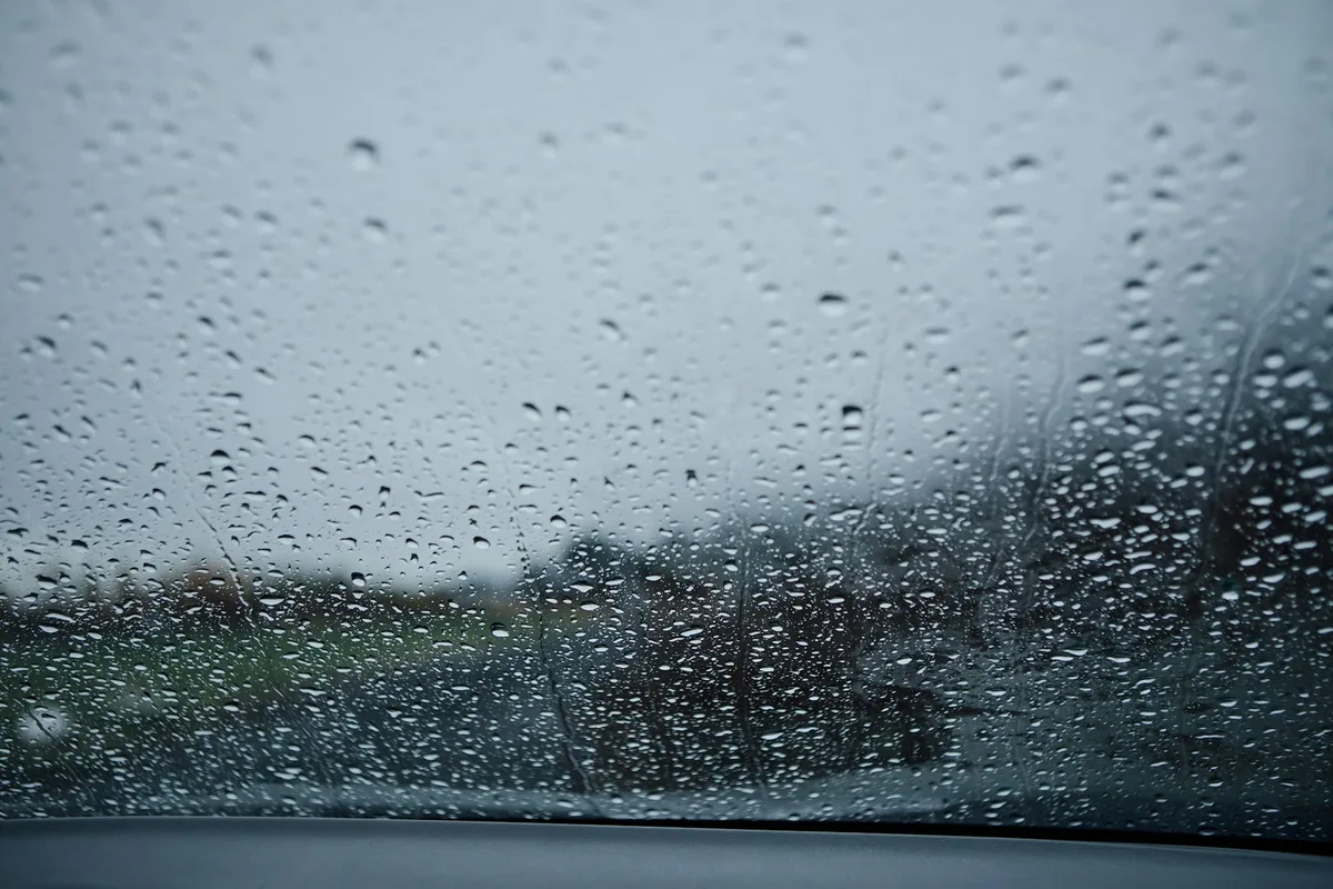 雨粒がびっしりついた車のフロントガラスを、運転席側から見たところ